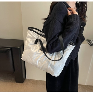 Gros plan d'un sac cabas matelassé blanc avec bandoulières en cuir noir sur l'épaule