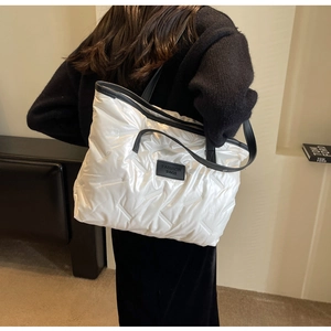 Détail d'un grand sac cabas matelassé blanc avec anses noires et étiquette mode