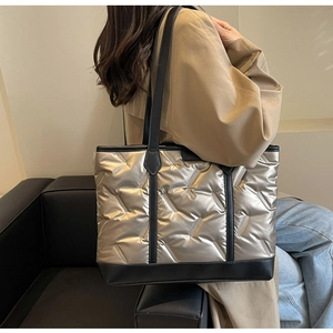 Close-up of metallic gold quilted tote bag with diamond pattern on a model