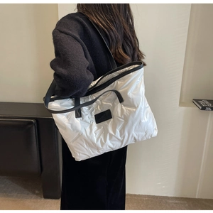 Détail d'un sac cabas blanc matelassé avec doubles poignées et texture douce gonflée