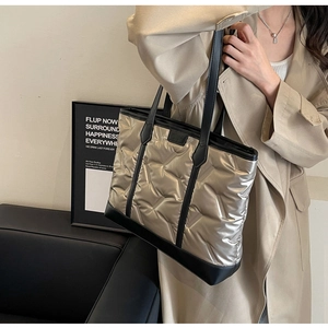Detail of champagne gold quilted tote bag with V-shaped texture and leather handles