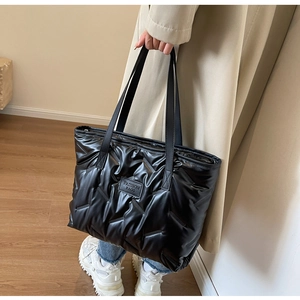 Détail du sac fourre-tout matelassé noir en nylon brillant avec patch logo mode