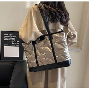 Detailed shot of champagne gold quilted tote bag featuring black leather trim and handles