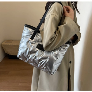 Détail d'un sac cabas argenté matelassé avec bandoulière noire et écusson logo mode