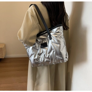 Détail du sac cabas matelassé argenté avec bandoulières noires et étiquette de mode