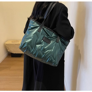 Détail du sac fourre-tout matelassé vert métallisé avec logo sur bandoulière noire