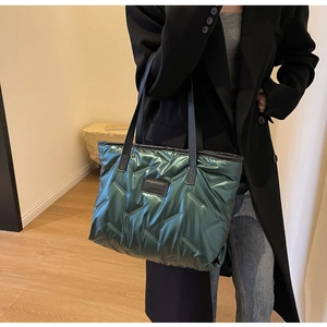 Détail d'un sac cabas matelassé vert émeraude avec des anses en cuir noir sur l'épaule