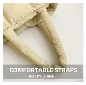 Detailed macro view of the cream-colored padded wide shoulder strap on this tote bag