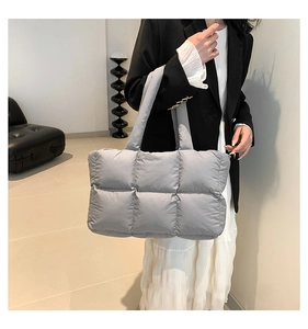 Detail of grey quilted down tote bag featuring soft padded texture and wide shoulder strap