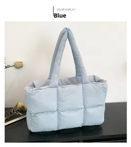 Detail of light blue quilted tote bag with soft down-like padding on dark wood