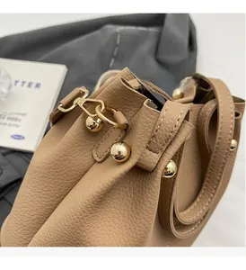 Close-up of beige lychee texture leather bucket bag with golden bead hardware detail