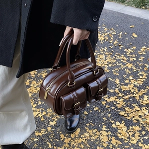 Retro brown glossy bowling handbag with buckle pockets shown in a stylish street setting