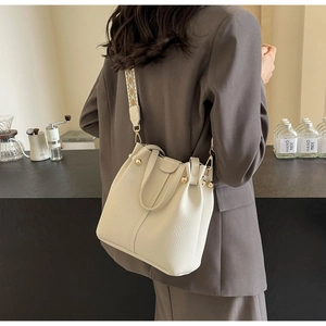 White leather bucket bag with geometric wide strap shown from a back view