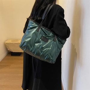 Sac fourre-tout matelassé vert métallisé avec poignées en cuir noir porté par un mannequin