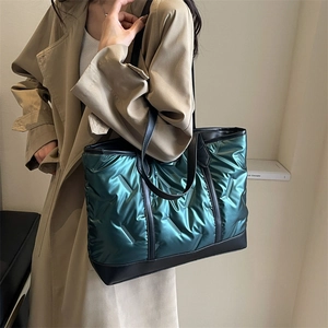 Quilted metallic green tote bag with black leather straps shown on model for winter fashion