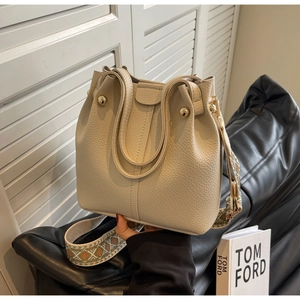 Detail of cream pebbled leather bucket bag with bohemian embroidered strap and gold buckle