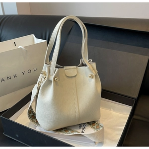 Macro view of creamy white bucket bag with pebble leather texture and ethnic strap