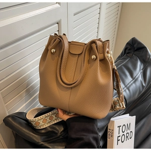 Detail of caramel leather bucket bag with jacquard strap and polished metal rivets