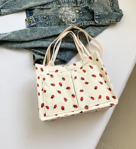 Detail of white corduroy tote bag with strawberry print and dual front pockets