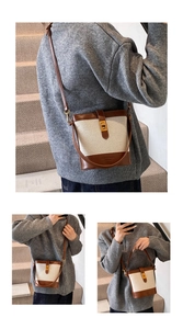 Detail of retro canvas bucket bag featuring dark brown leather trim and gold twist lock
