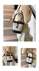 Detail of canvas bucket bag showing the gold-tone metal lock and leather trim texture