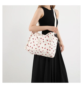 Detail of corduroy tote bag with strawberry print showing side pocket and woven shoulder strap