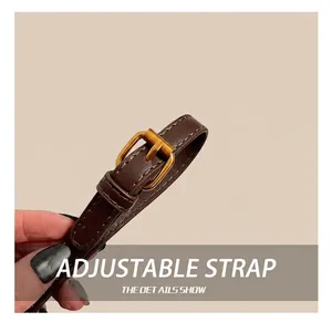 Macro detail of brown leather adjustable shoulder strap with vintage gold metal buckle