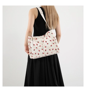 Detailed view of cream corduroy tote bag with red strawberry print and two front pockets