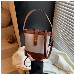 Detail of canvas bucket bag showing gold twist lock and brown leather stitching