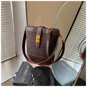 Detail of the brown textured fabric bucket bag with leather trim and gold metal lock