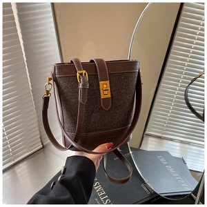 Detail of dark brown leather and tweed bucket bag with elegant gold twist lock closure