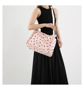 Detail of pink corduroy tote bag with strawberry prints and white shoulder strap