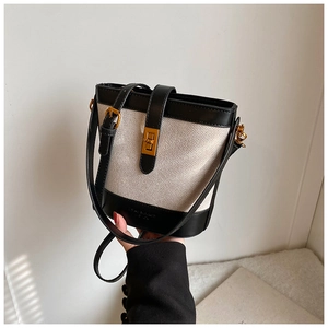 Detail of vintage canvas bucket bag with black leather trim and gold twist lock closure