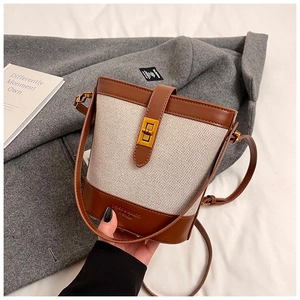 Detail view of the brown leather and beige canvas bucket bag with gold metal buckle