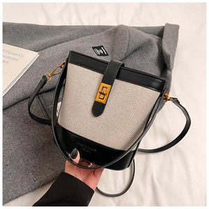 Detail of canvas bucket bag with black leather trim and golden twist-lock closure