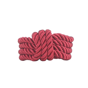 Close-up of a woven burgundy napkin ring made of lustrous braided cord with intricate knotting