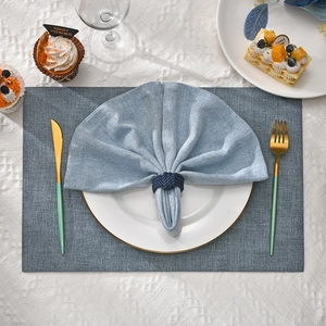 Close-up of woven deep blue placemat and napkin ring on a geometric white tablecloth