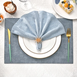 Golden sunburst napkin ring set with light blue linen cloth and elegant gold cutlery decor