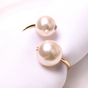 Elegant gold napkin ring featuring dual cream pearls with subtle rhinestone accents on white fabric