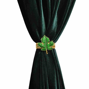 Detail of green maple leaf curtain tieback with gold edges on velvet fabric