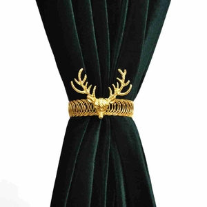 Golden deer head curtain tieback with flexible metal spring on a dark green velvet drape