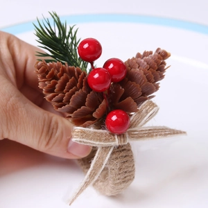 Christmas pine cone and red berry napkin ring with twine bow held over a white plate