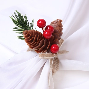 Detail of pine cone Christmas napkin ring with red berries and twine wrapped loop