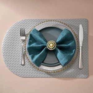 Détail du rond de serviette doré avec perle et strass sur une serviette bleue