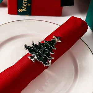 Silver Christmas tree napkin ring with green enamel finish and star on red cloth
