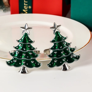 Set of two green enamel Christmas tree napkin rings with silver stars and dots on a white plate