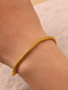Close-up of golden snake bone chain bracelet with detailed metallic scale texture