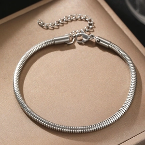 Polished titanium steel snake chain bracelet with adjustable lobster clasp on gold surface