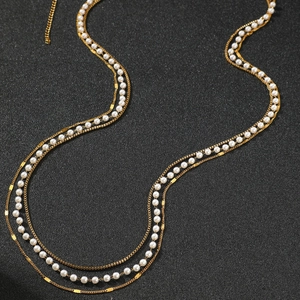 Elegant multi-layer gold chain with white pearls on a textured black background