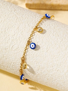 Détail d'une chevillère bohème dorée avec perles œil bleu et cristaux clairs sur pierre